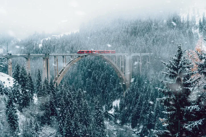 Scenic view of train on viaduct in Switzerland forest in winter