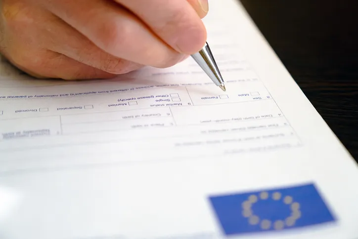 Schengen visa, questionnaire. Hand with pen completing a questionary