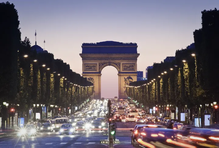 Pretty night time illuminations of the Impressive Arc de Triomphe (1833) along the famous tree lined Avenue des Champs-Elysees in Paris.