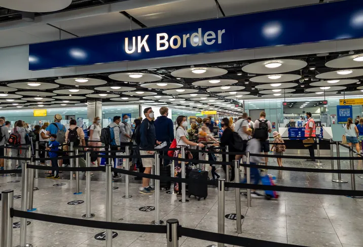 The UK borders at Terminal 5 with arriving international travel passengers waiting for immigration control and passport checks.