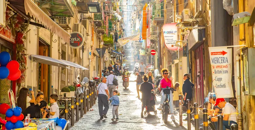 Naples, Italy - 10 June, 2023: Sunny narrow street in Napoli old town, colorful Spagnoli (Spanish) quarter, people walking in the street.