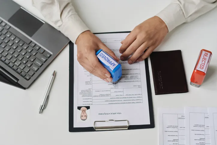 Top view of specialist of visa center approving visa putting stamp on document