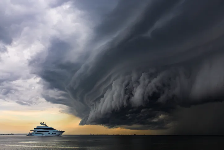 A massive storm moving in to land over the ocean forming into a "shelf cloud" while a luxury super yacht cruises in the water in Queensland, Australia.