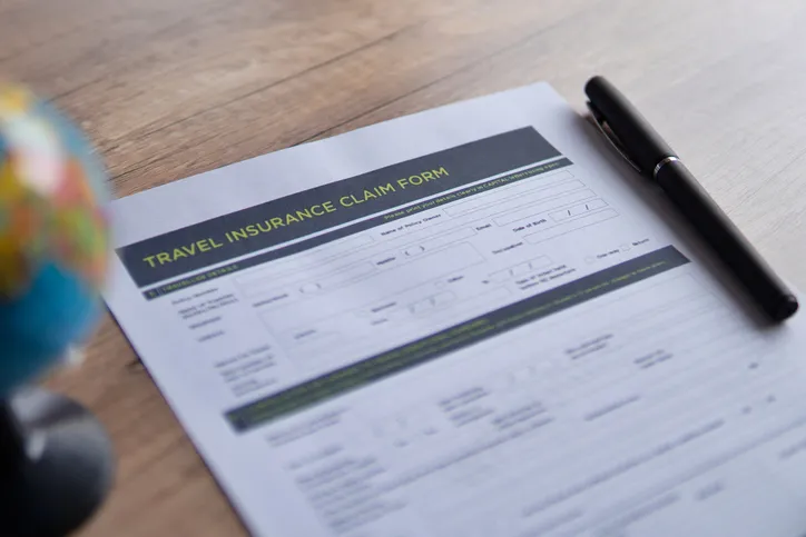 Selective focus image of travel insurance claim form on a wooden table. Travel, protection and insurance concept.