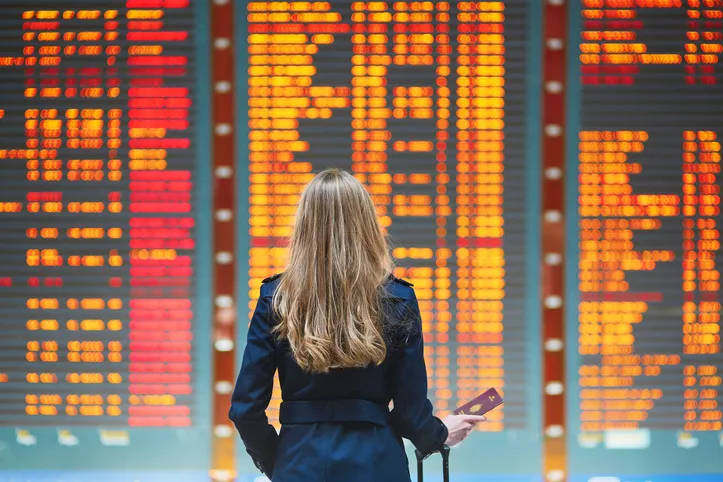 Beautiful young tourist girl near flight information board