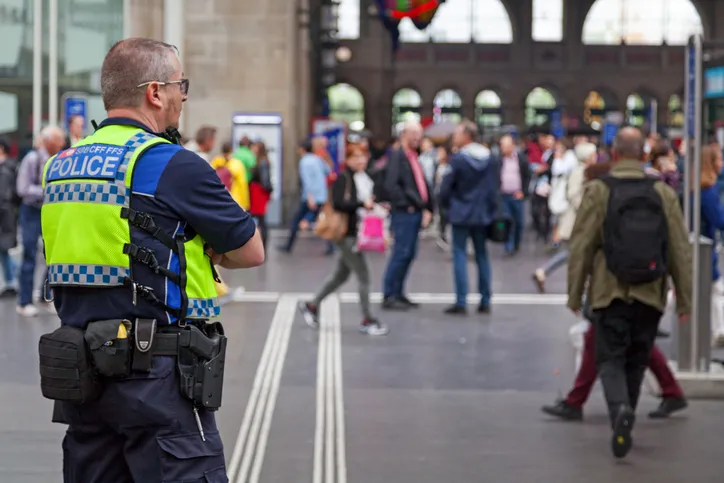 Police officer from the railway police checking at the crowd of travellers in Zürich Hauptbahnhof railway station