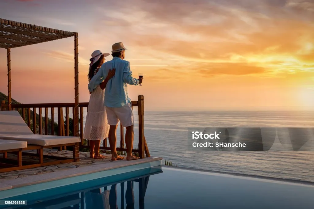 A romantic couple on summer vacation seduces the sunset over the Mediterranean Sea by the pool