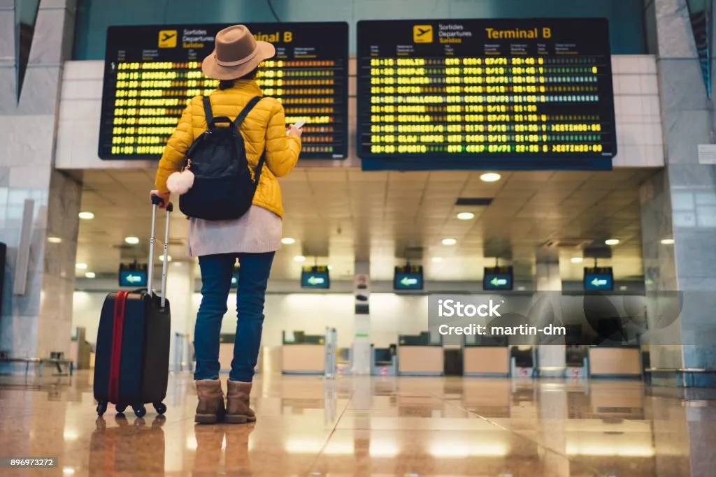 Young woman at the airport in Barcelona checking for the flight schedule